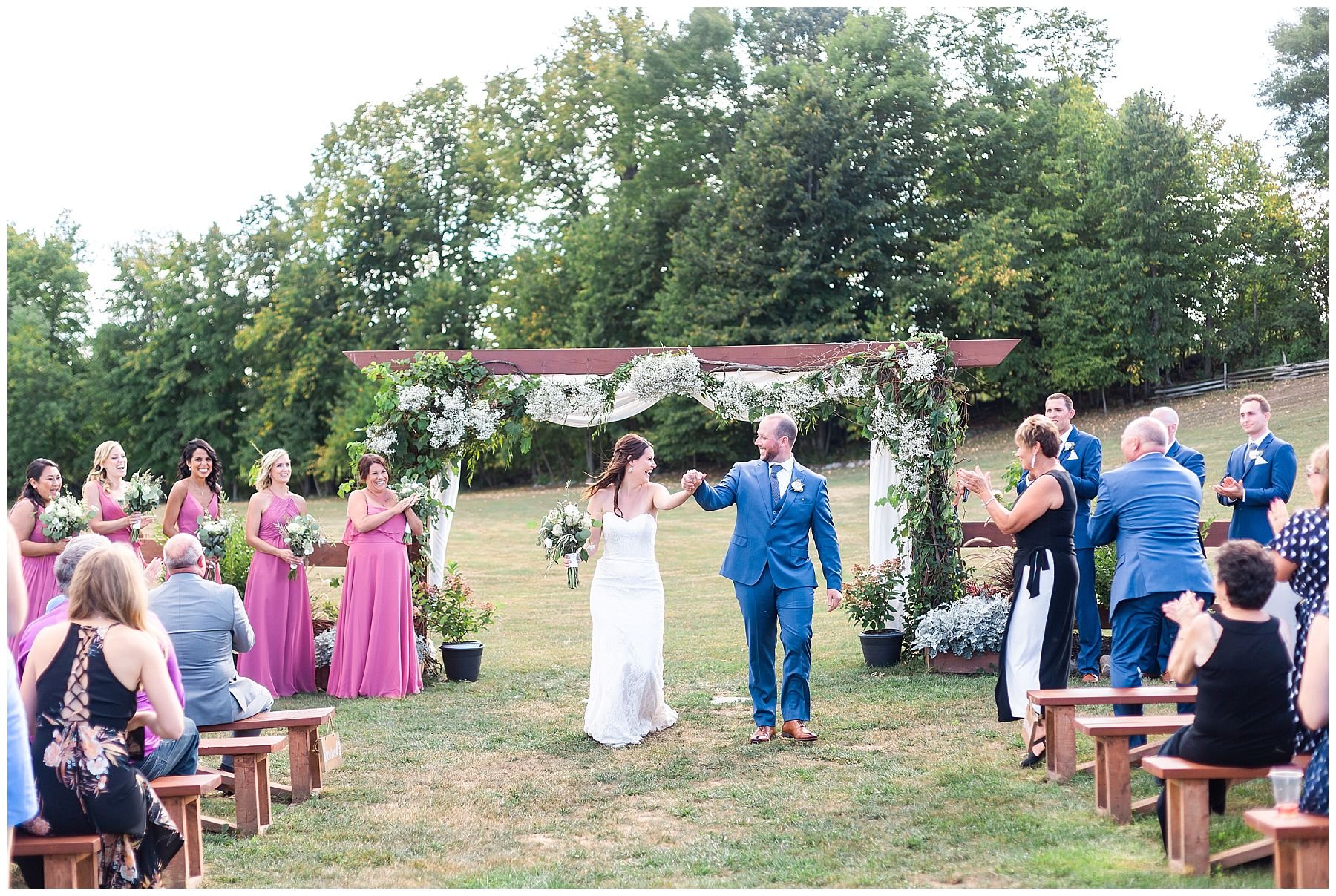 outdoor wedding ceremony under flower arch