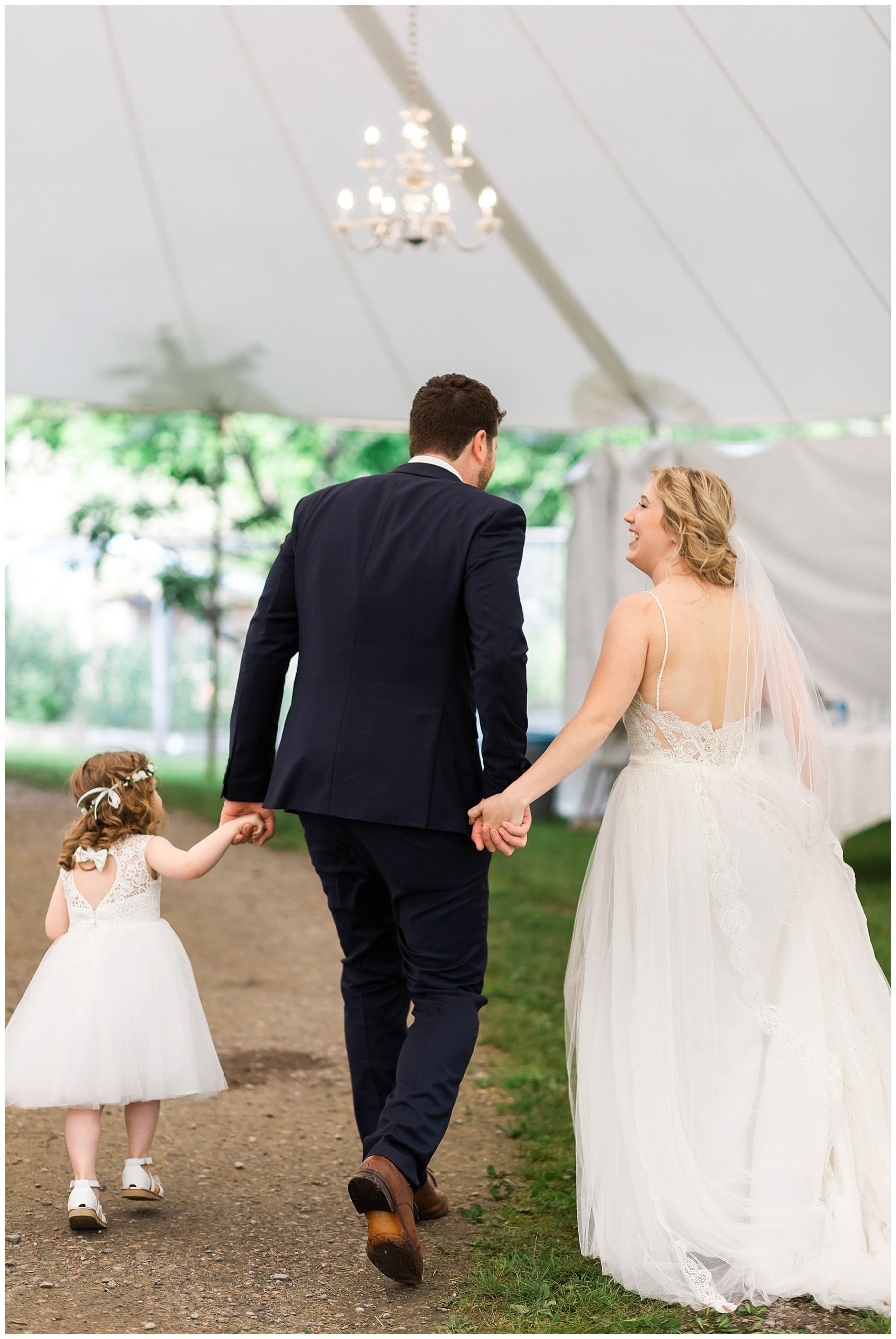 Bride and groom and flower girl walking hand in hand