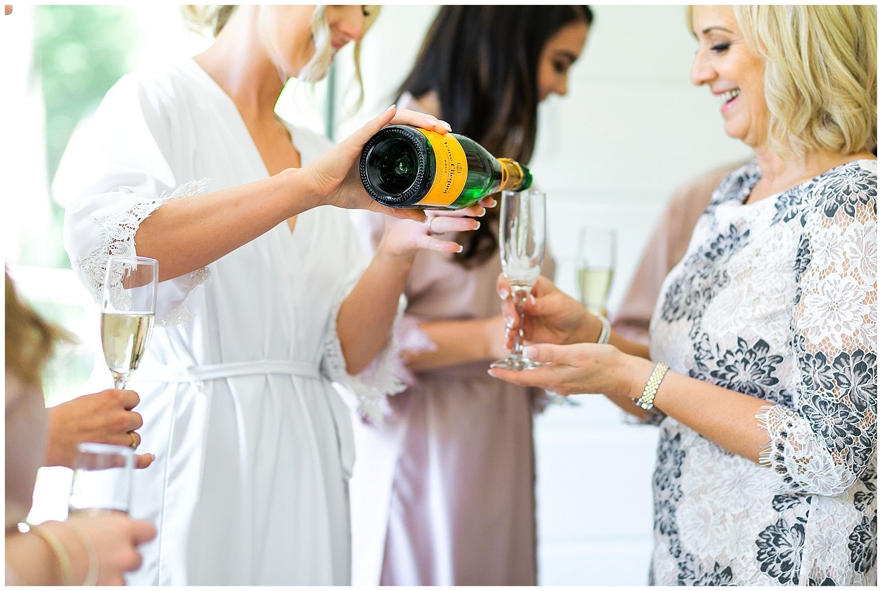 bride and bridesmaids in robes drinking champagne