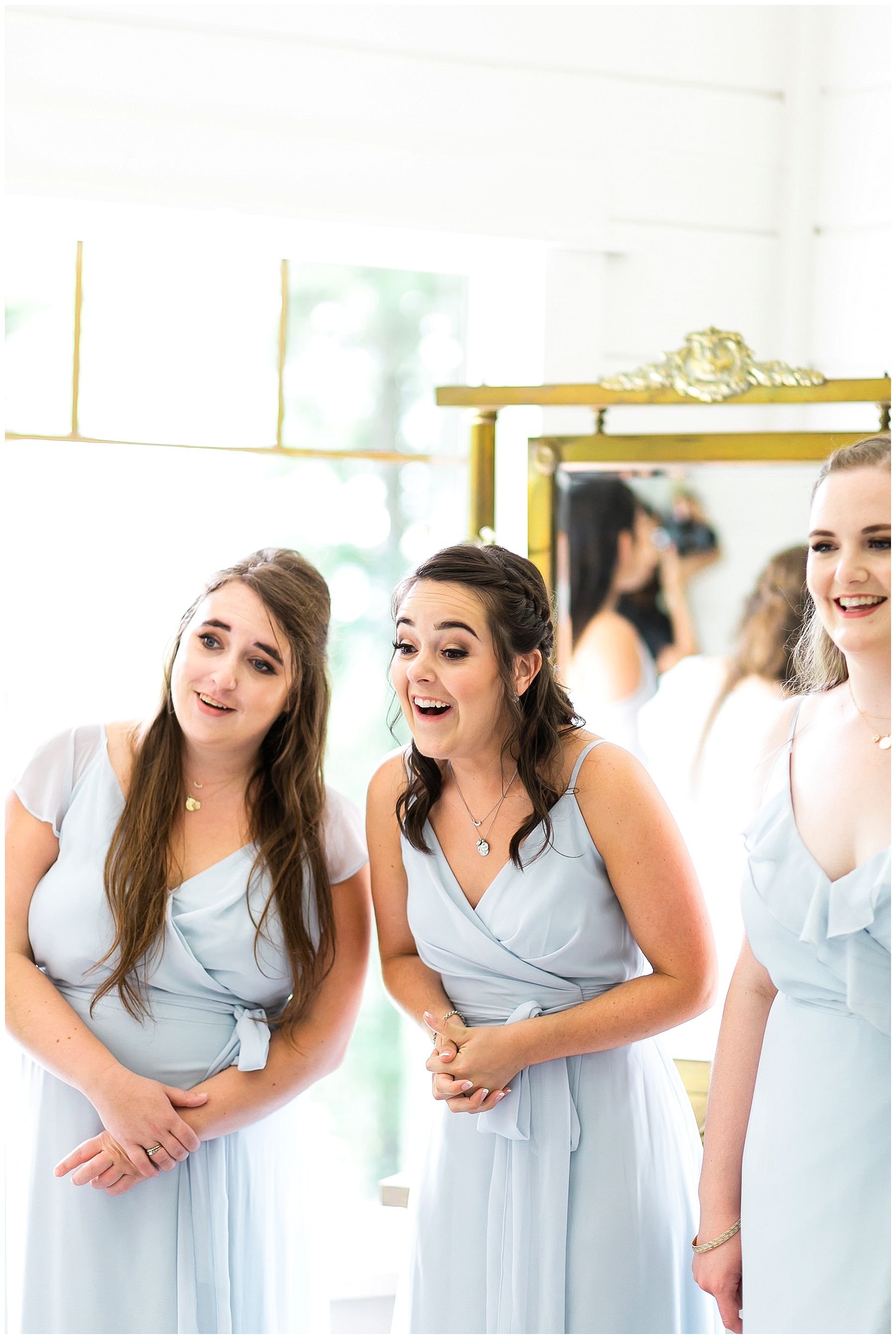 Pastel blue Bridesmaids sweet reactions looking at the bride