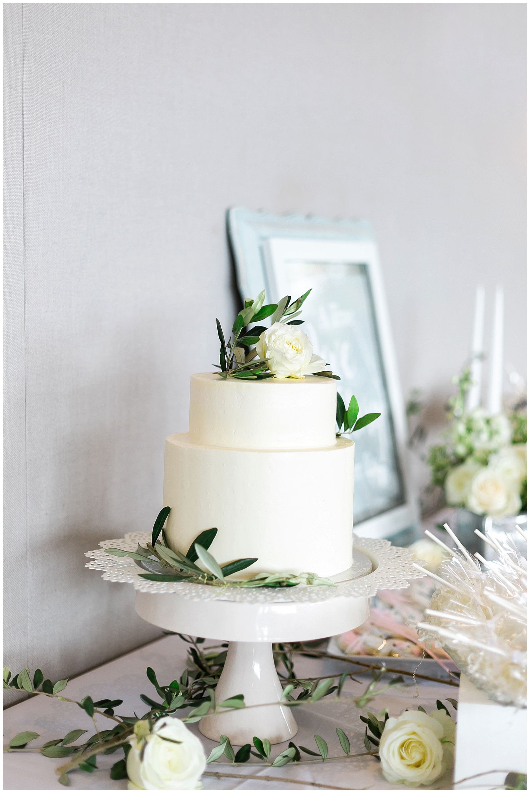 White wedding cake with olive branch and greenery.
