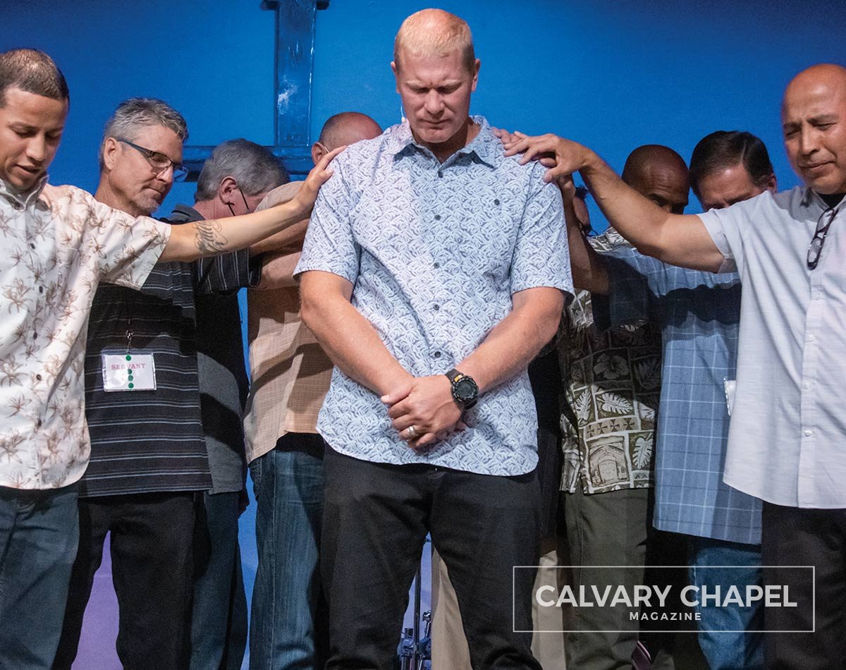 Pastors and elders laying hands on Pastor Phil