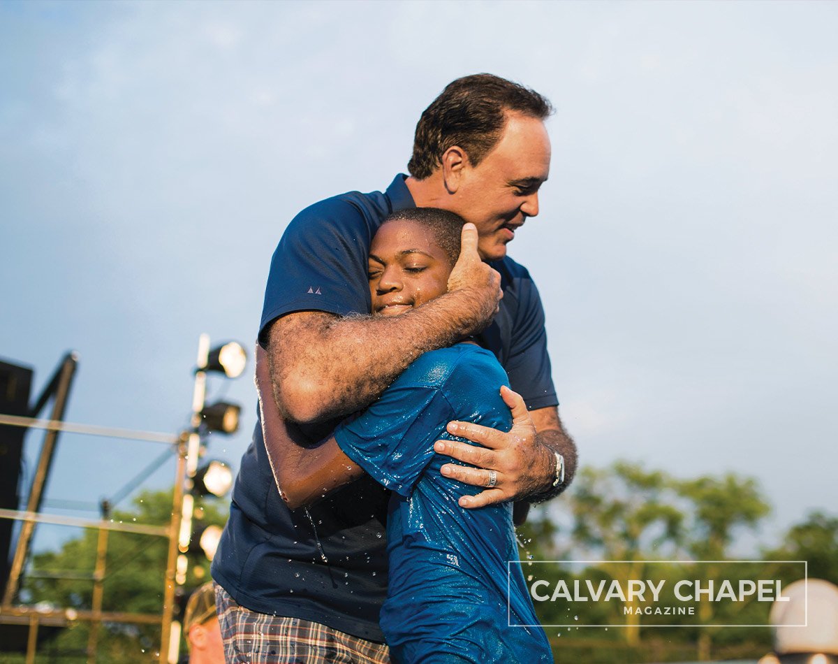 Guy hugs child after baptism