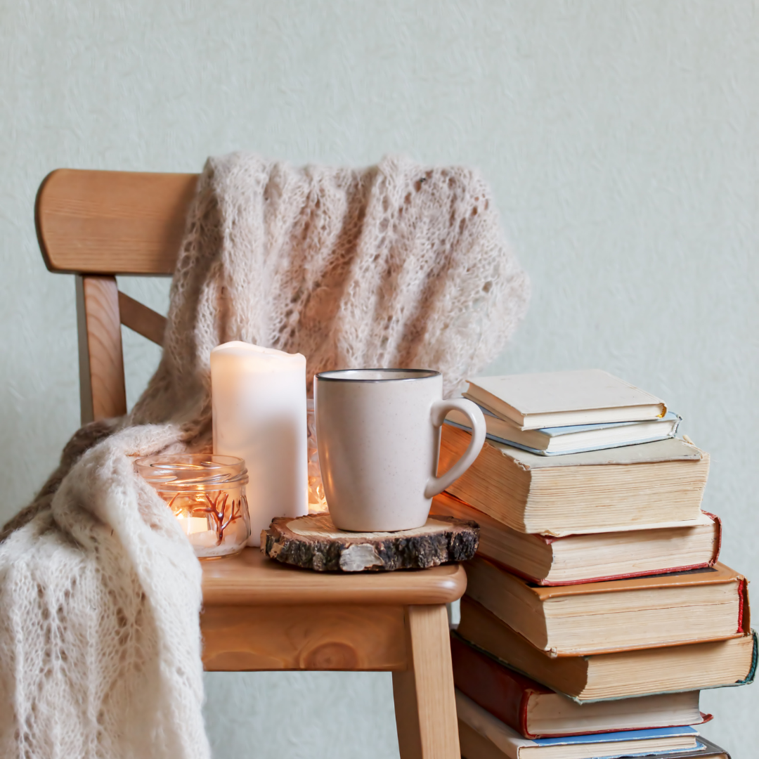 chair holding cup, candles and books