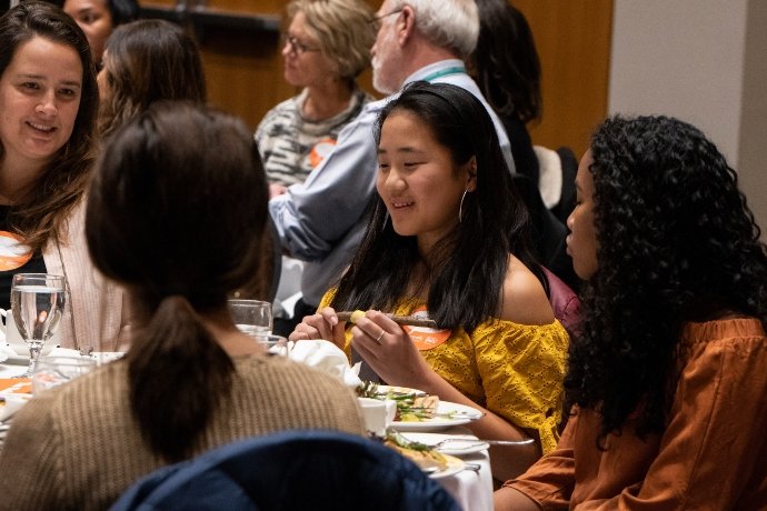 Young person speaking at a table with others listening