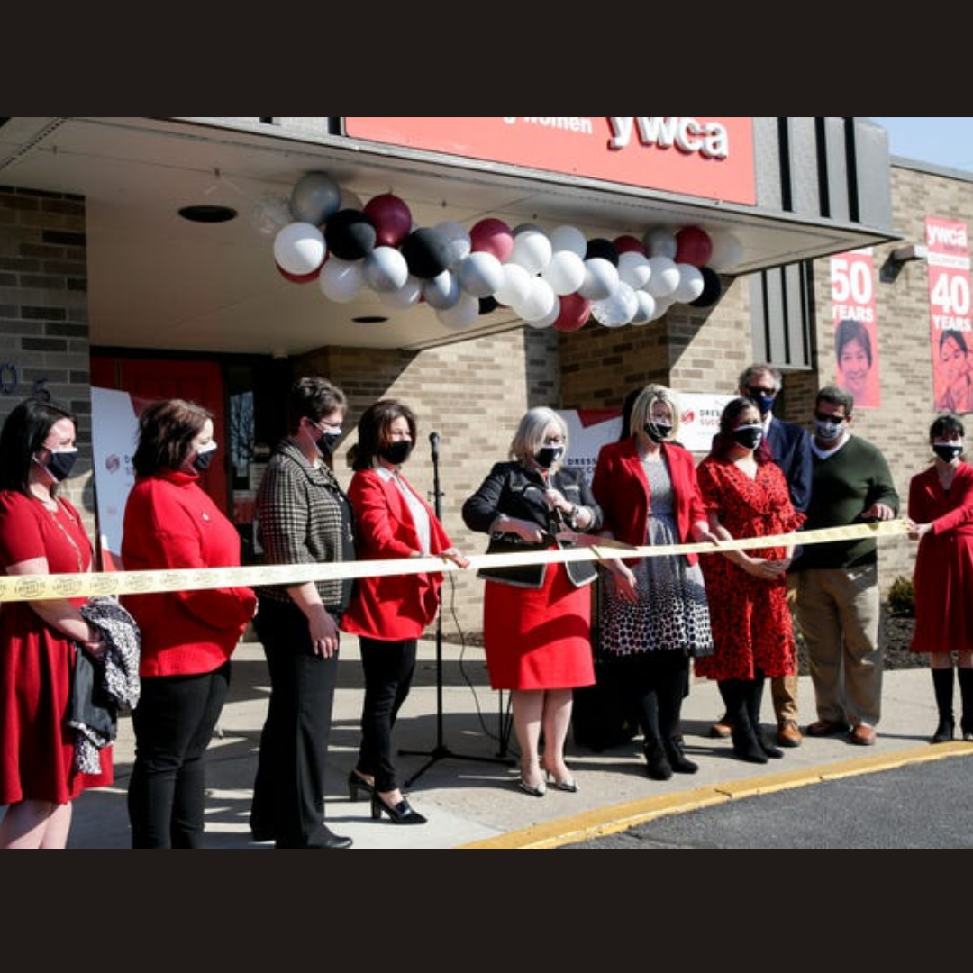 dress for success launch photo of women wearing red and black cutting a ribbon in front of YWCA