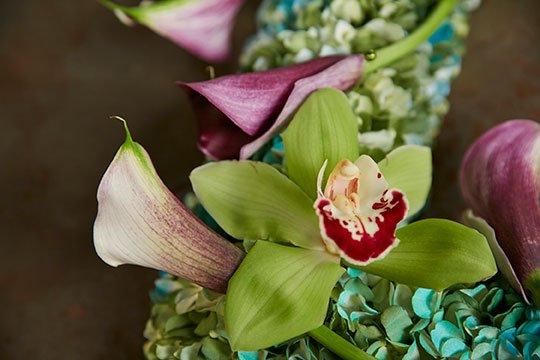 J uses decorative corsage pins to attach the orchids and callas to the wreath!