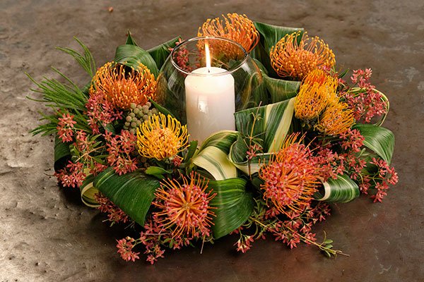 This Romantic Candle-light Centerpiece is created with Variegated Aspidistra Leaves- that J loops in a special technique and accents with Pincushion Protea and Beauty Bush