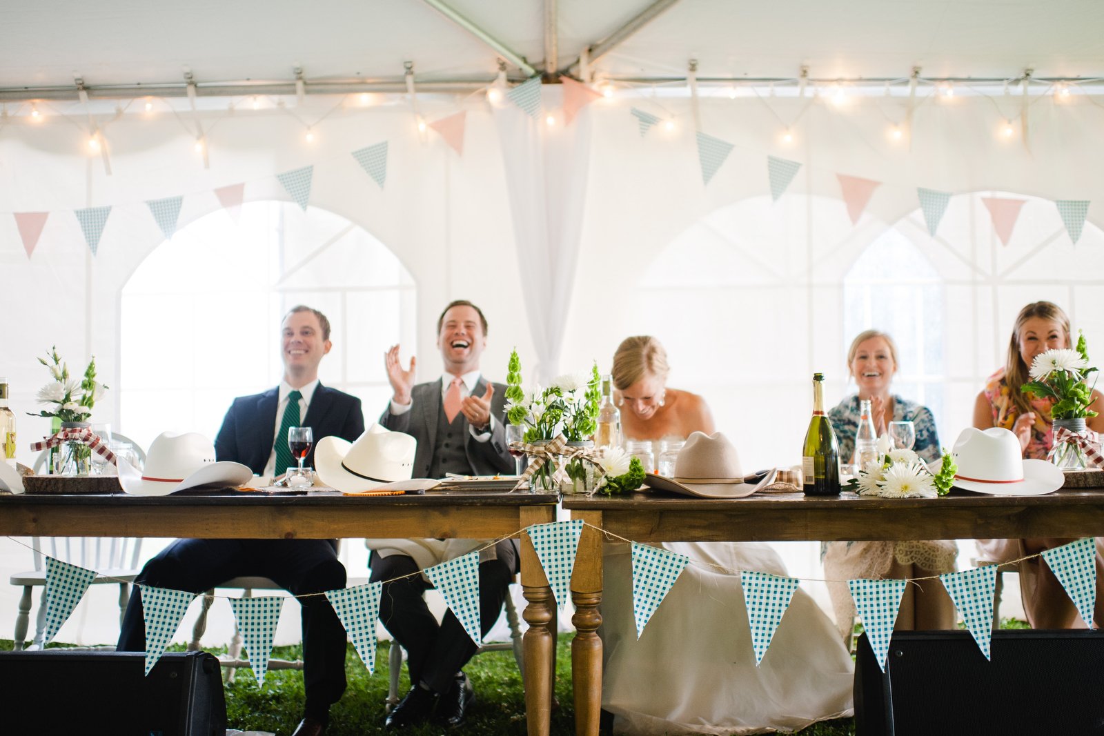 bride and groom laughing during speech | tent wedding reception | bunting wedding decor | ontario backyard wedding