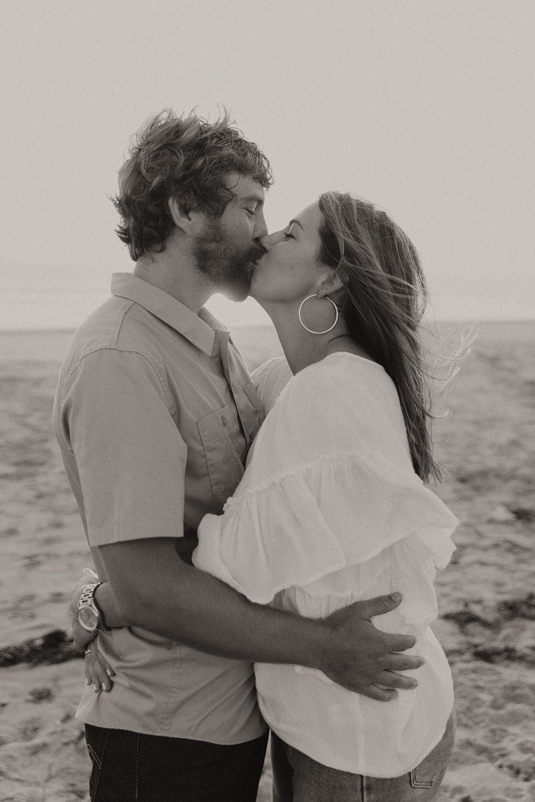 Black and white photo of couple kissing on the beach