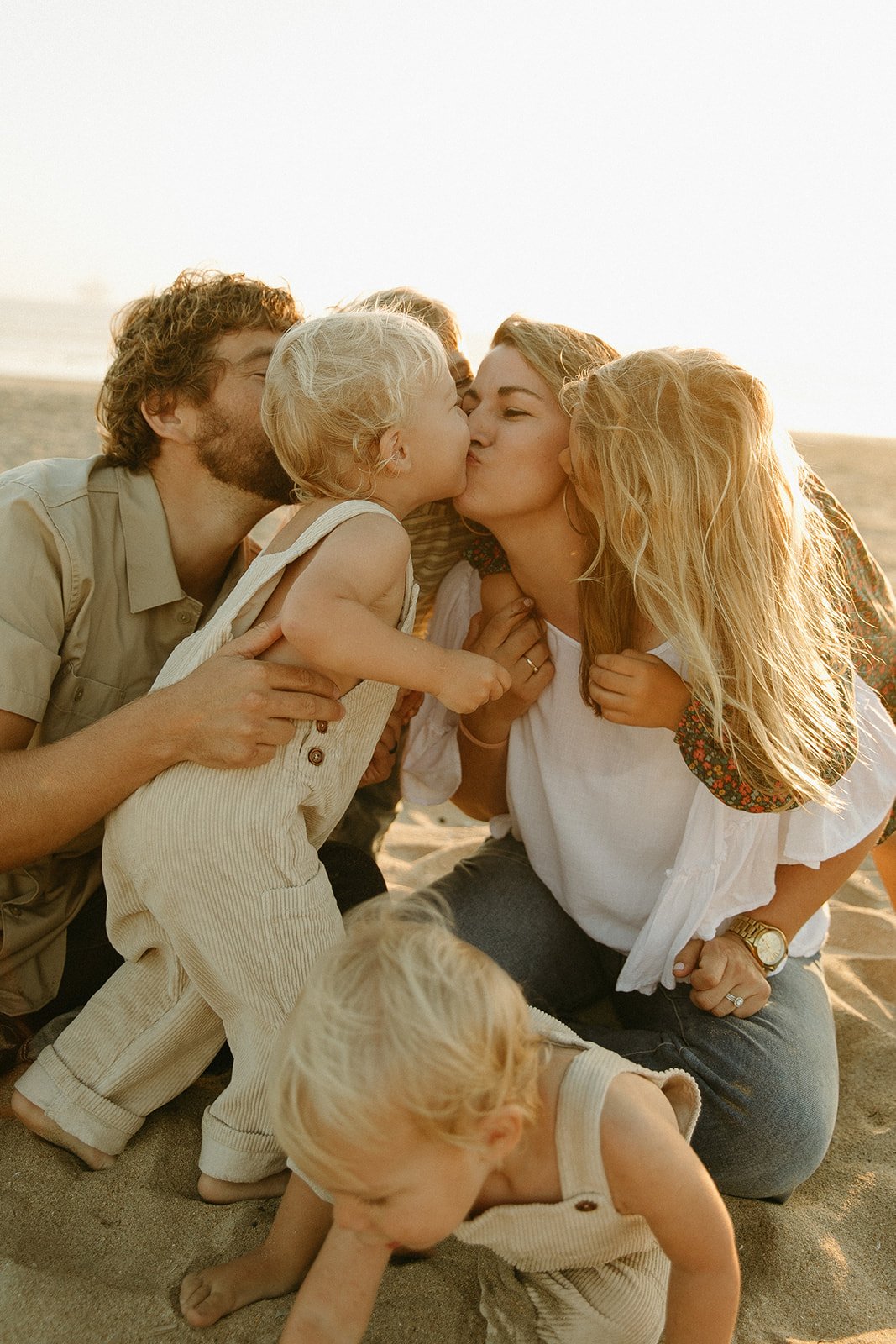 Parents kissing their kids on the beach