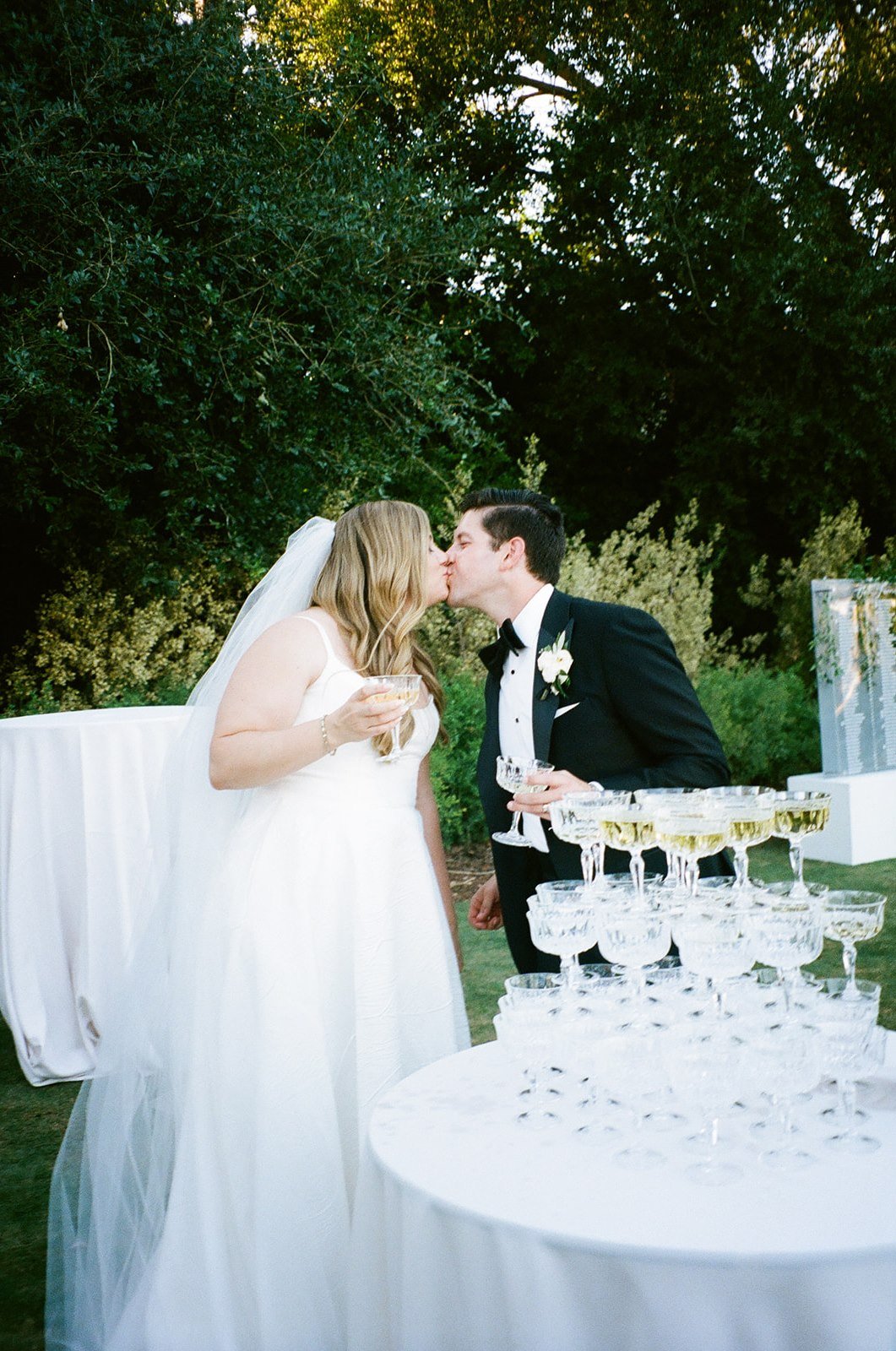 Film photos of bride and groom kissing near champagne tower