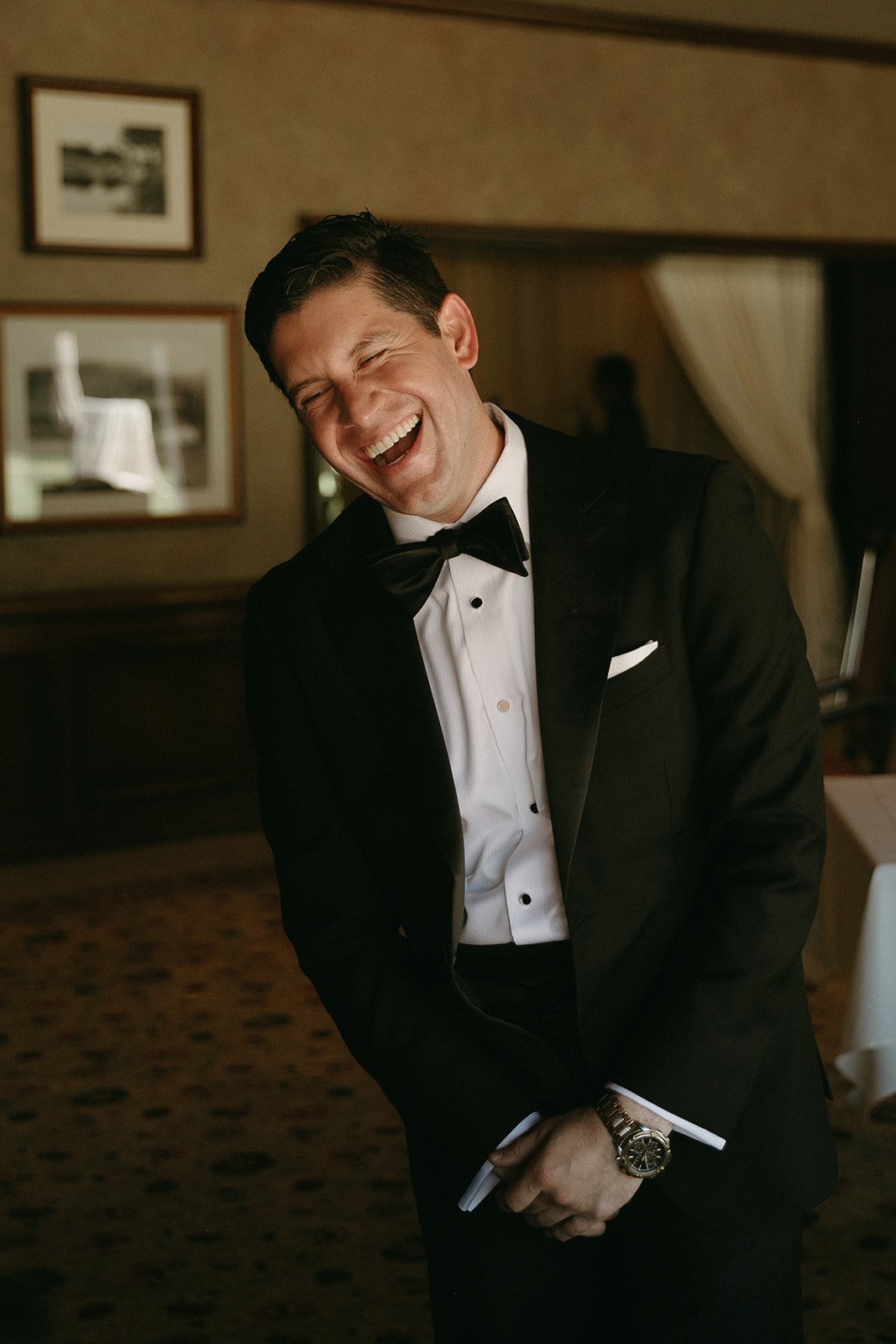 Groom laughing while getting ready