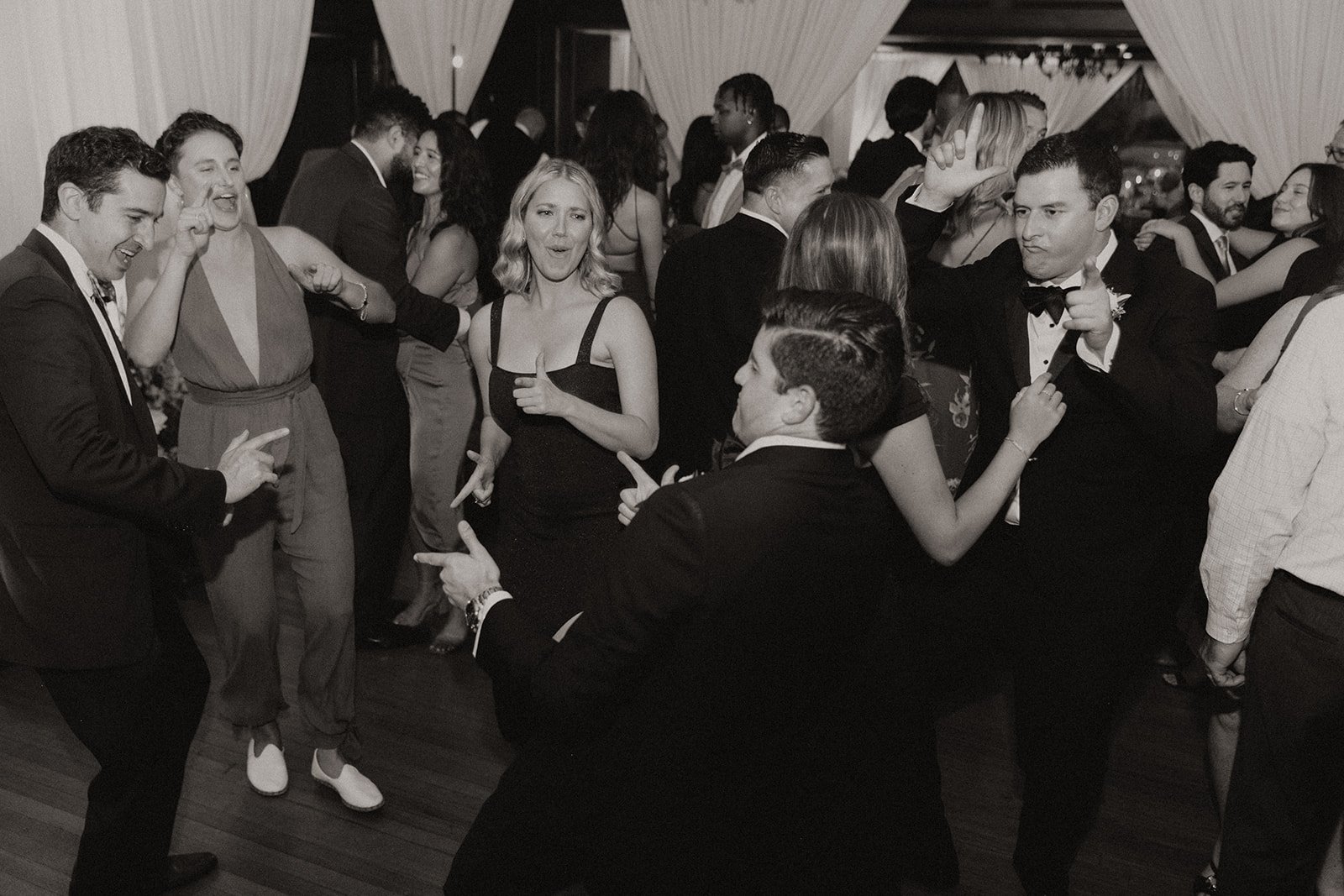 Black and white photo of family and friends dancing at wedding reception