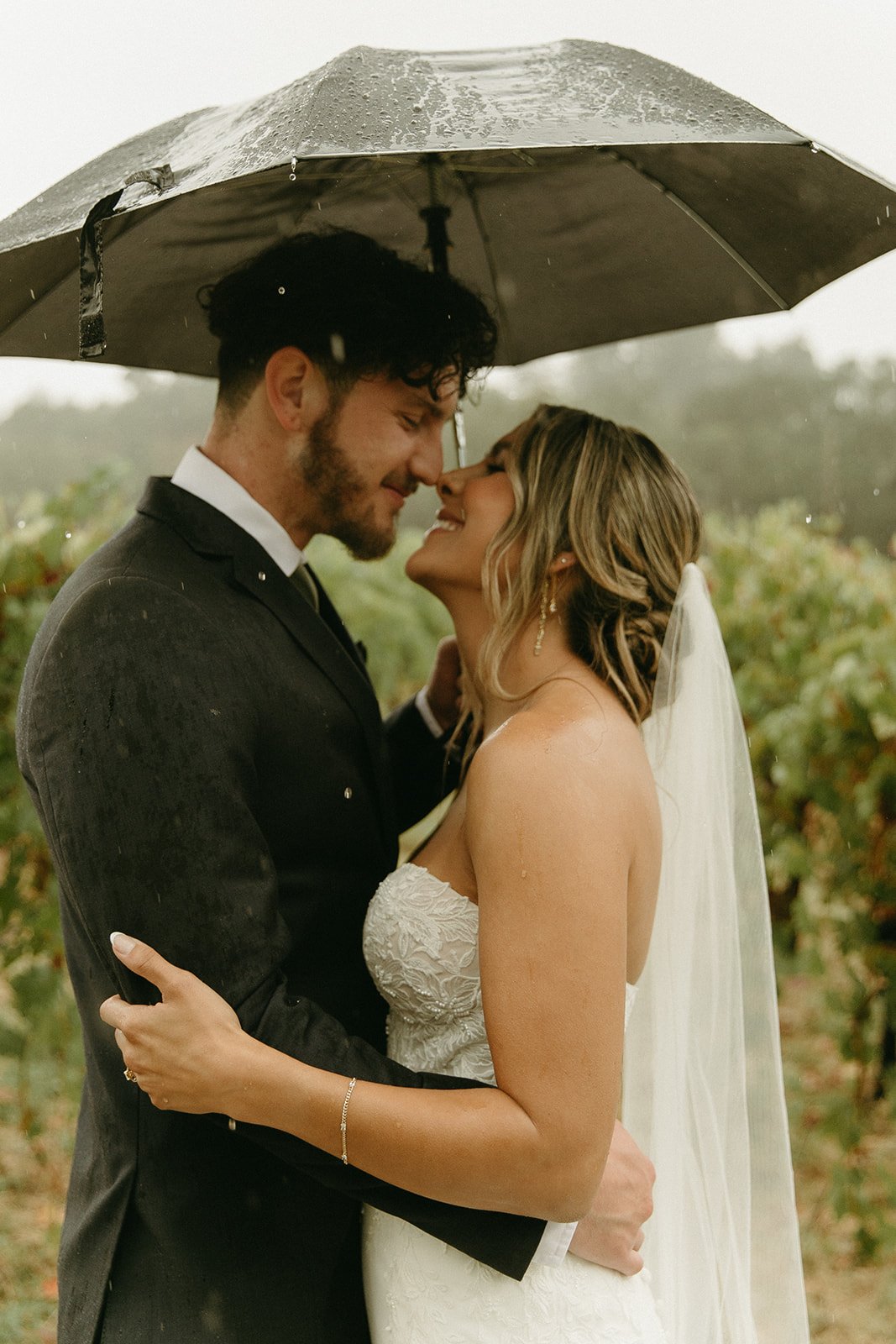Bride and groom smiling in the rain