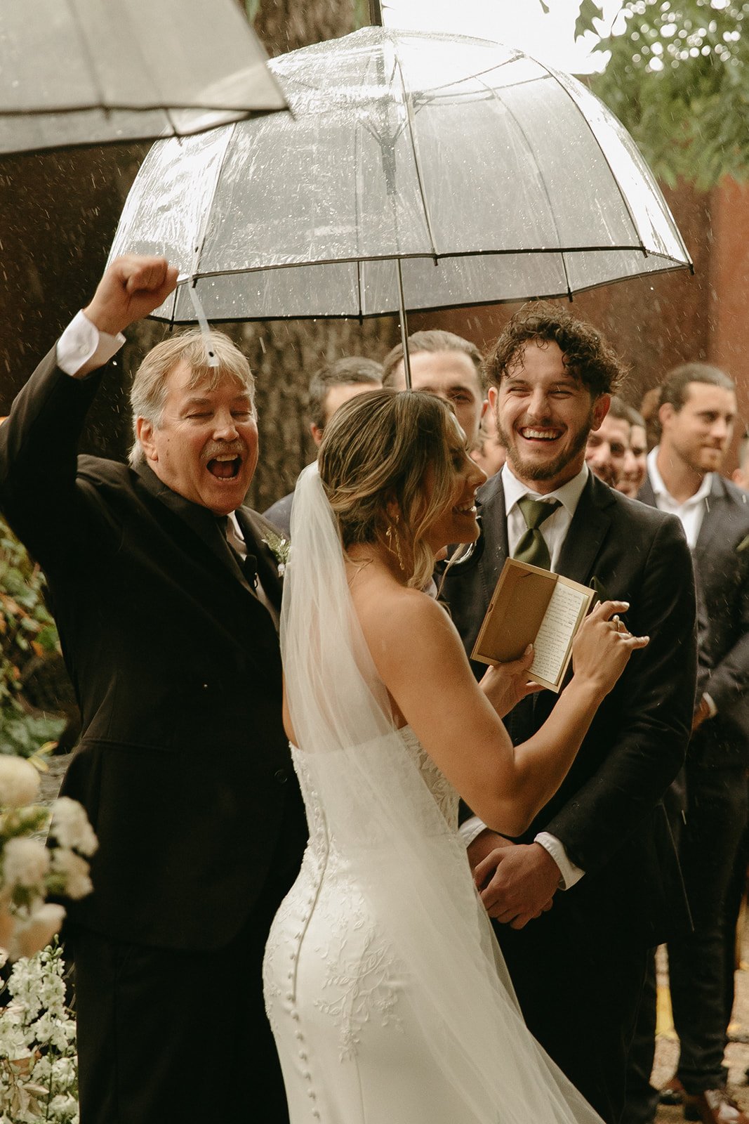 Bride and groom smiling during wedding ceremony in the rain