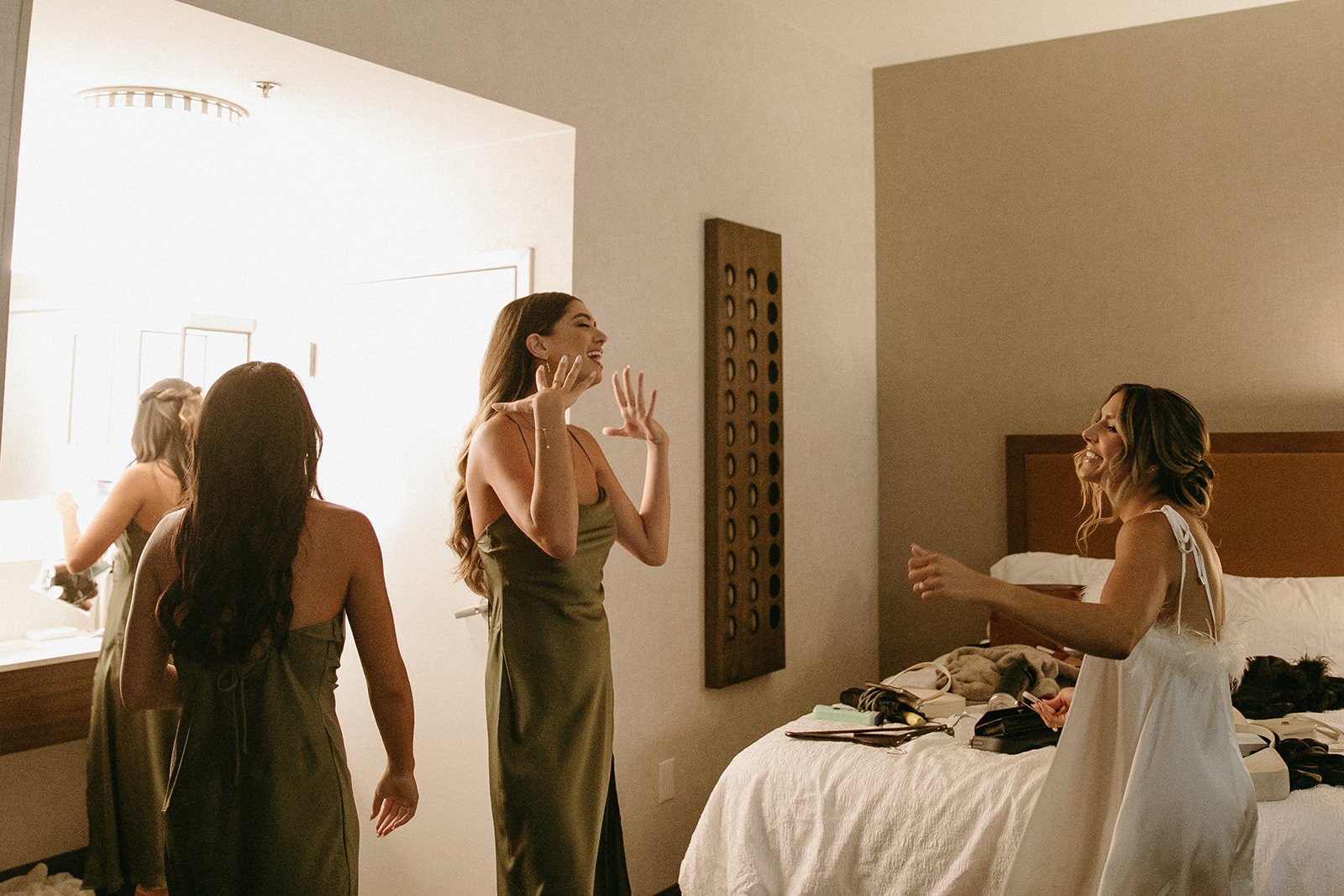 Bride and bridesmaids dancing and singing in hotel room