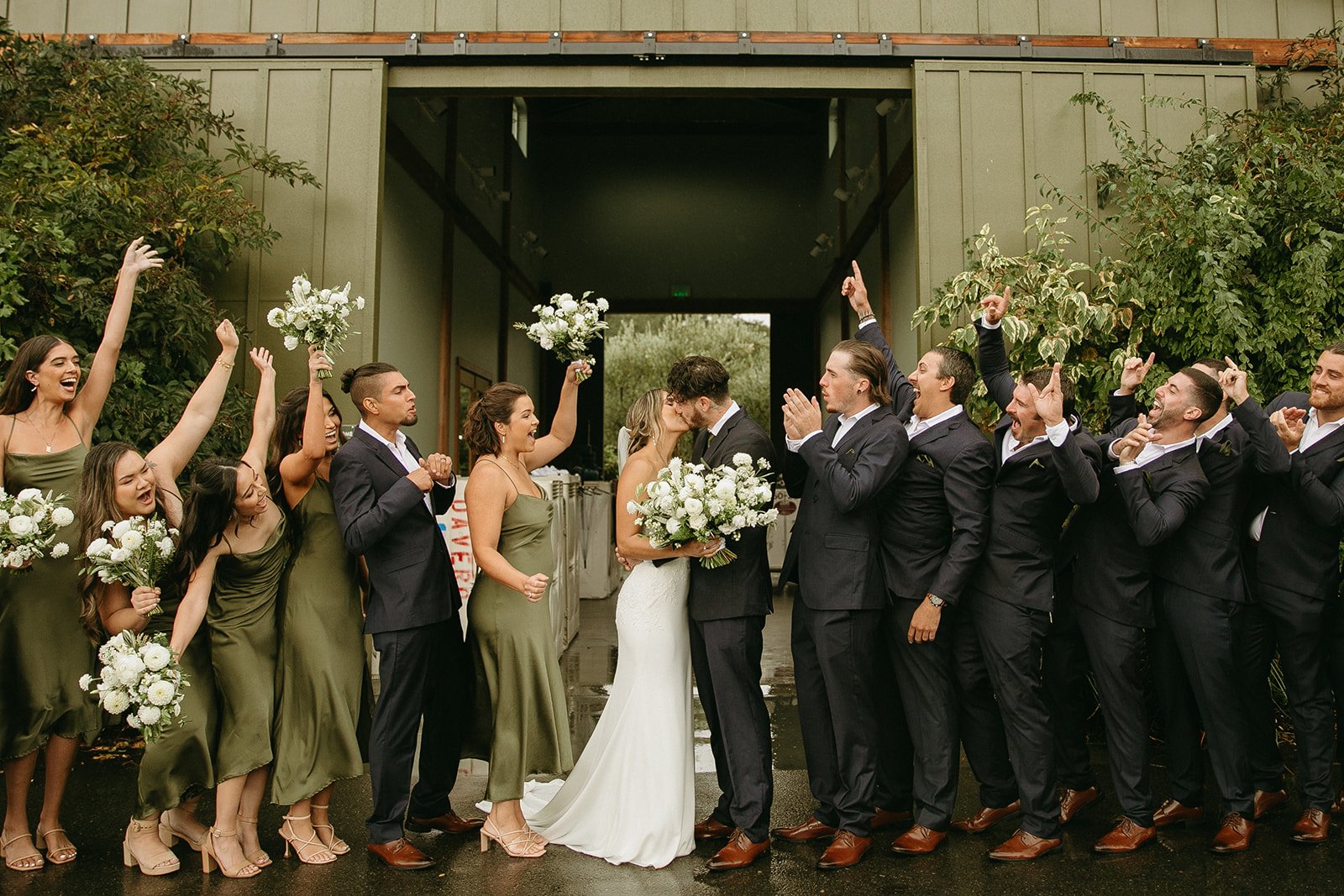 Bride and groom kissing with bridal party around