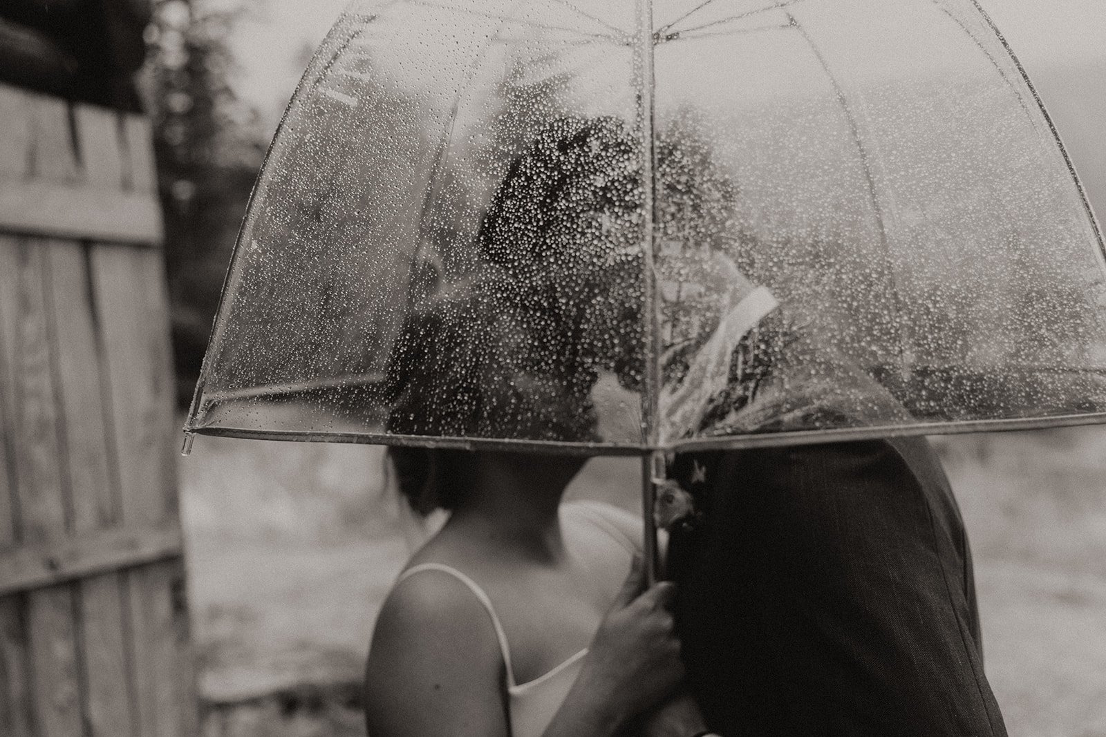Bride and groom looking at one another under an umbrella