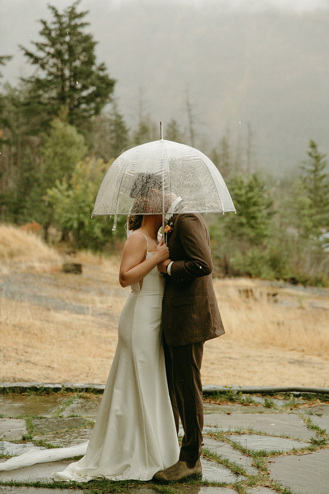 Bride and groom kissing under an umbrella