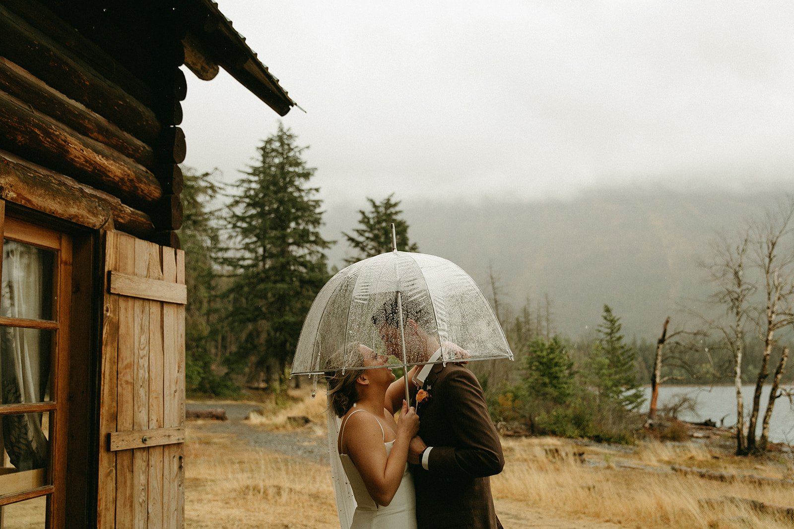 Bride and groom looking at one another under an umbrella
