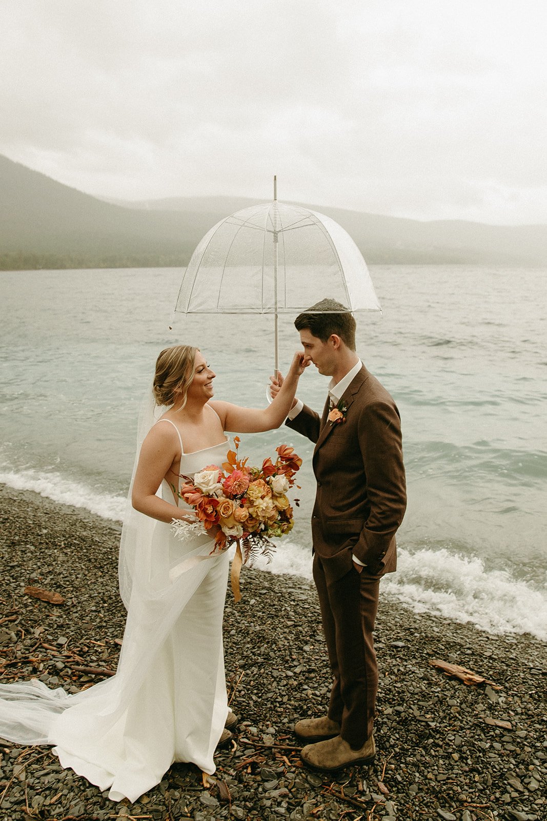 Bride wiping tears off grooms face at Glacier national park