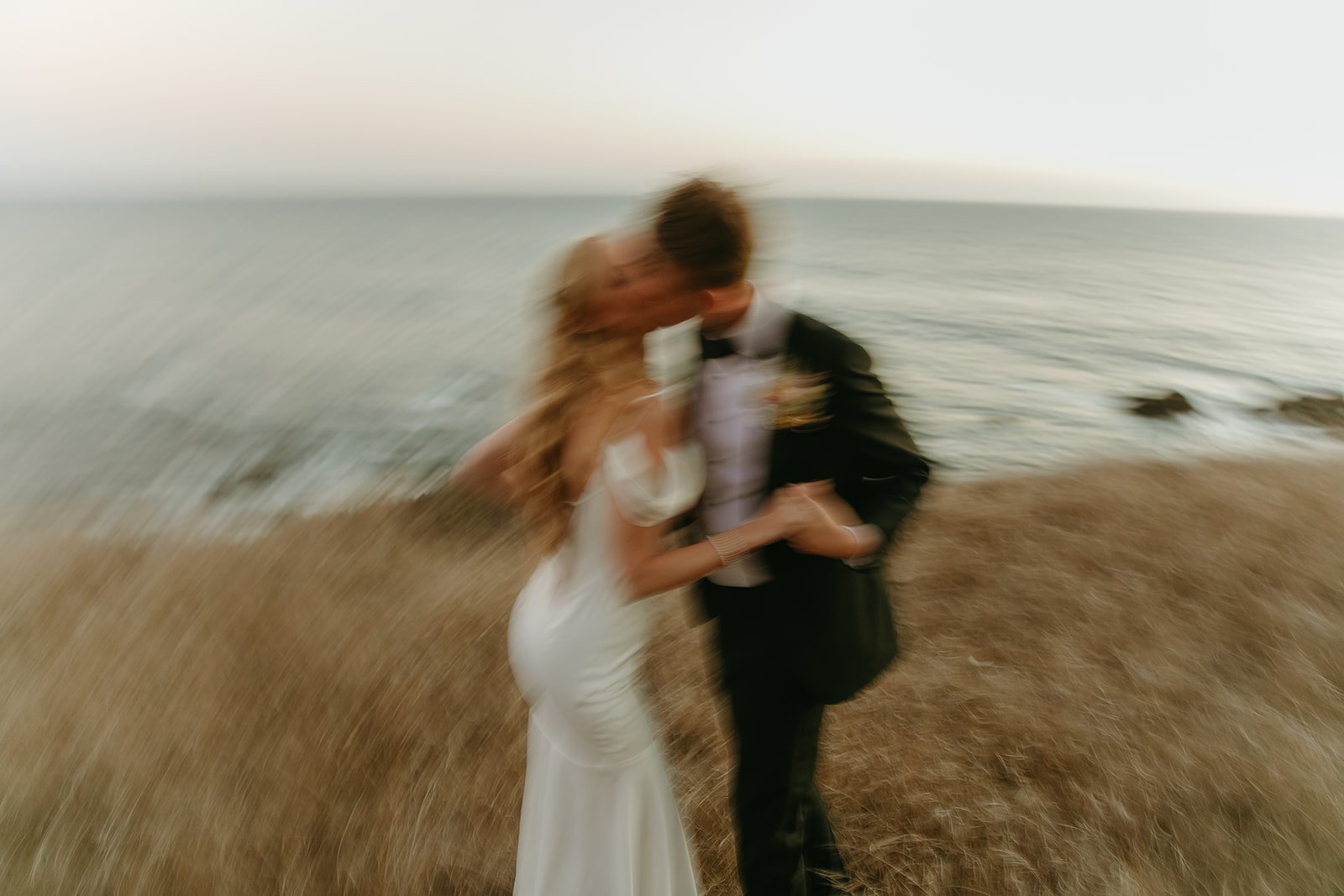 Bride and groom dancing on the coast during sunset