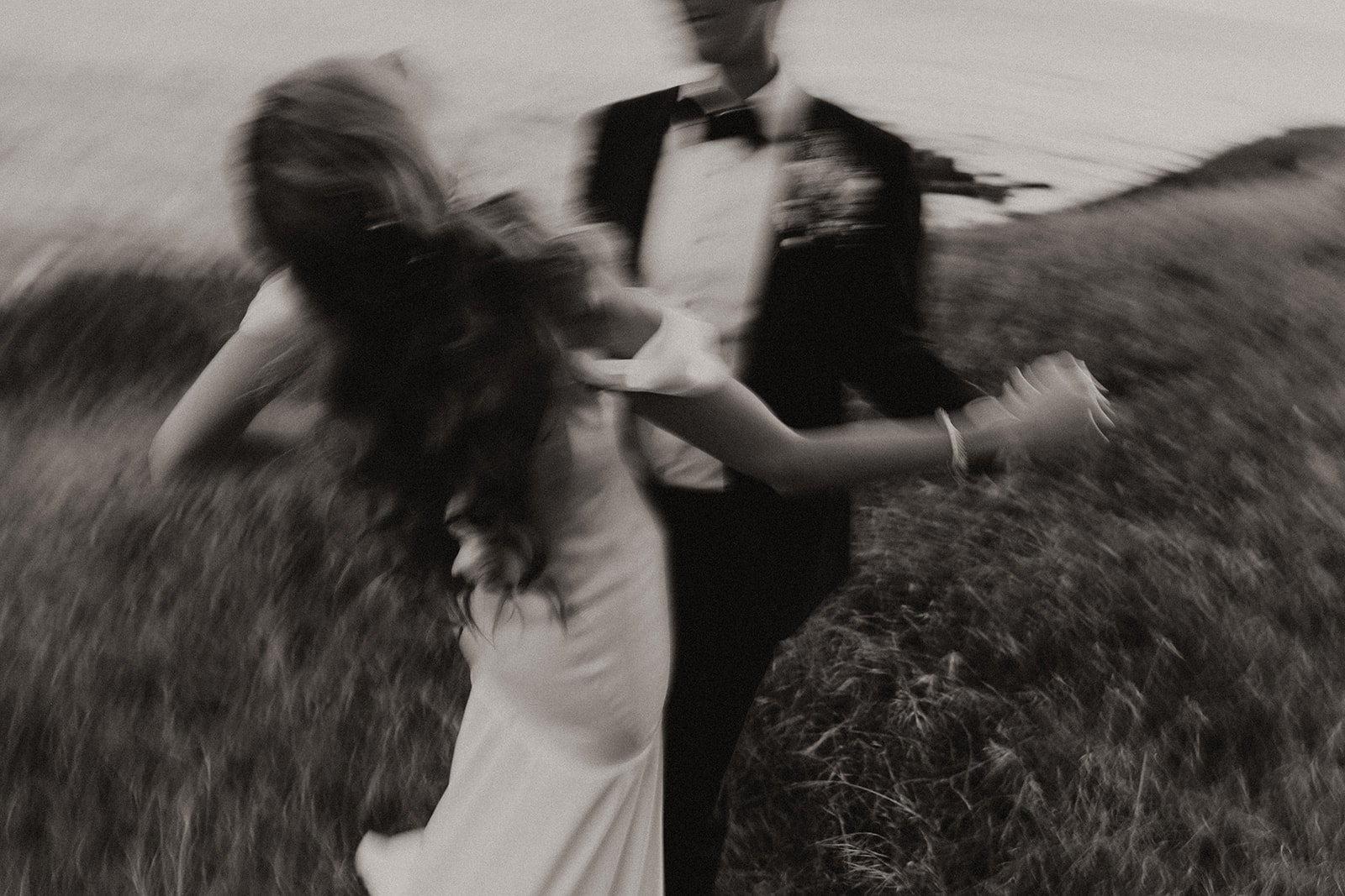 Bride and groom dancing on the coast during sunset in black and white