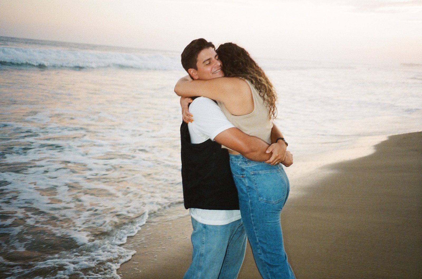 Newport Beach engagement photo session with cute couple hugging on the beach during golden hour on film