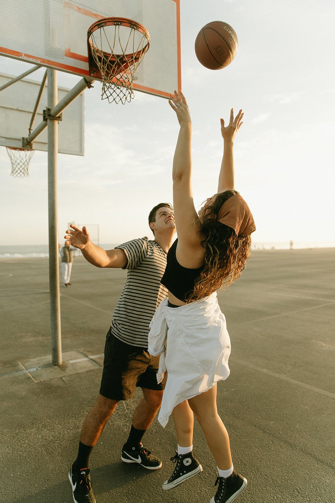 Newport Beach engagement photo session with couple playing basketball at a basketball court