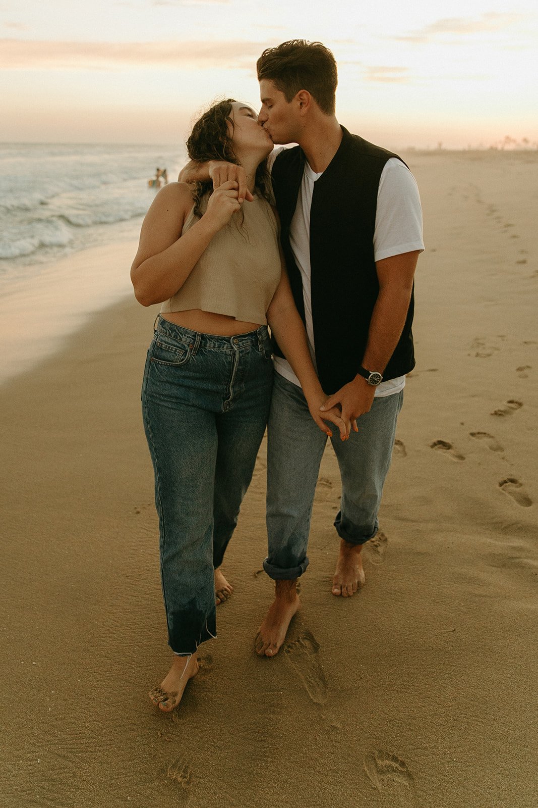 Newport Beach Engagement photo session walking and kissing on the beach during sunset