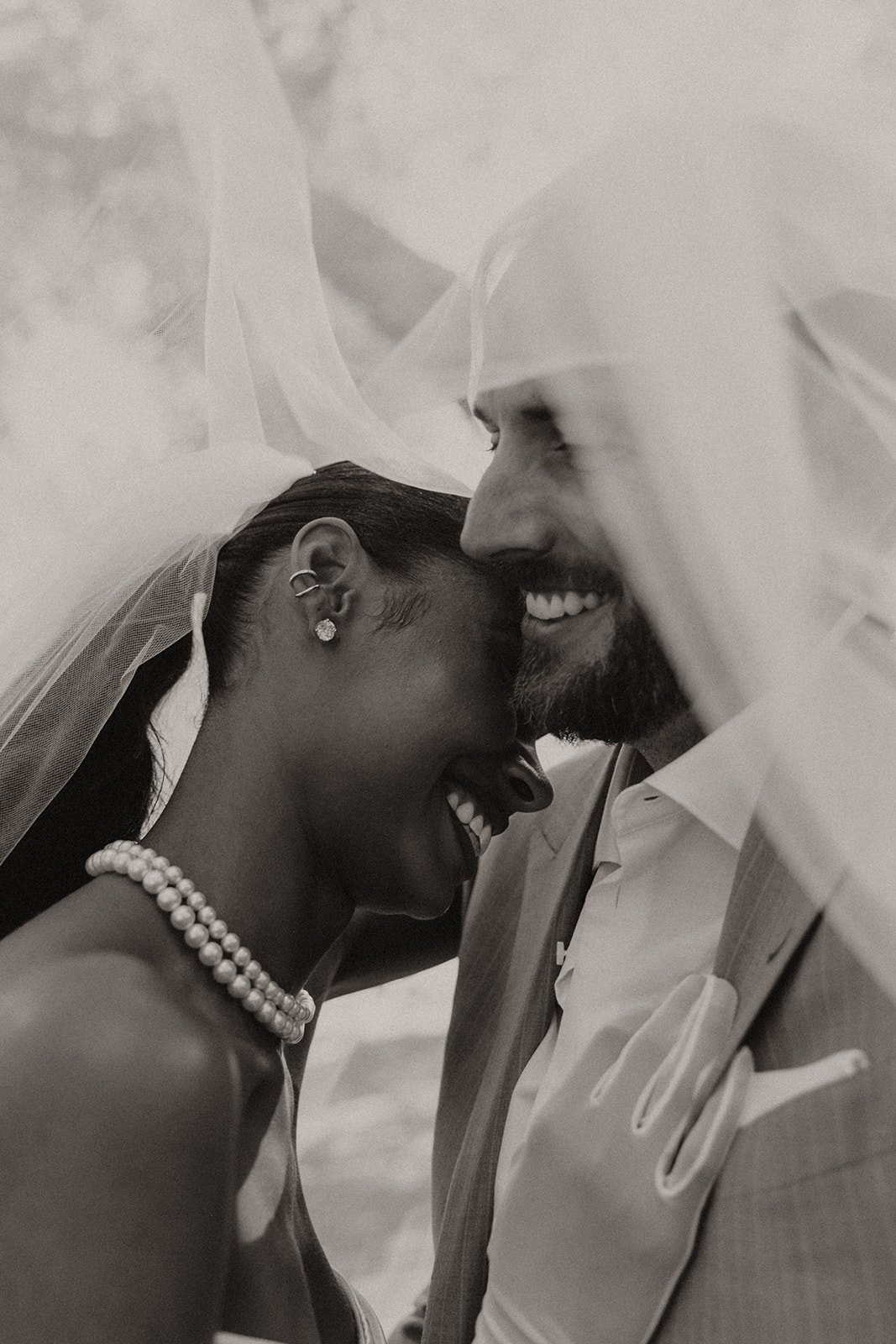 Black and white photo of Bride and groom kissing under the brides veil
