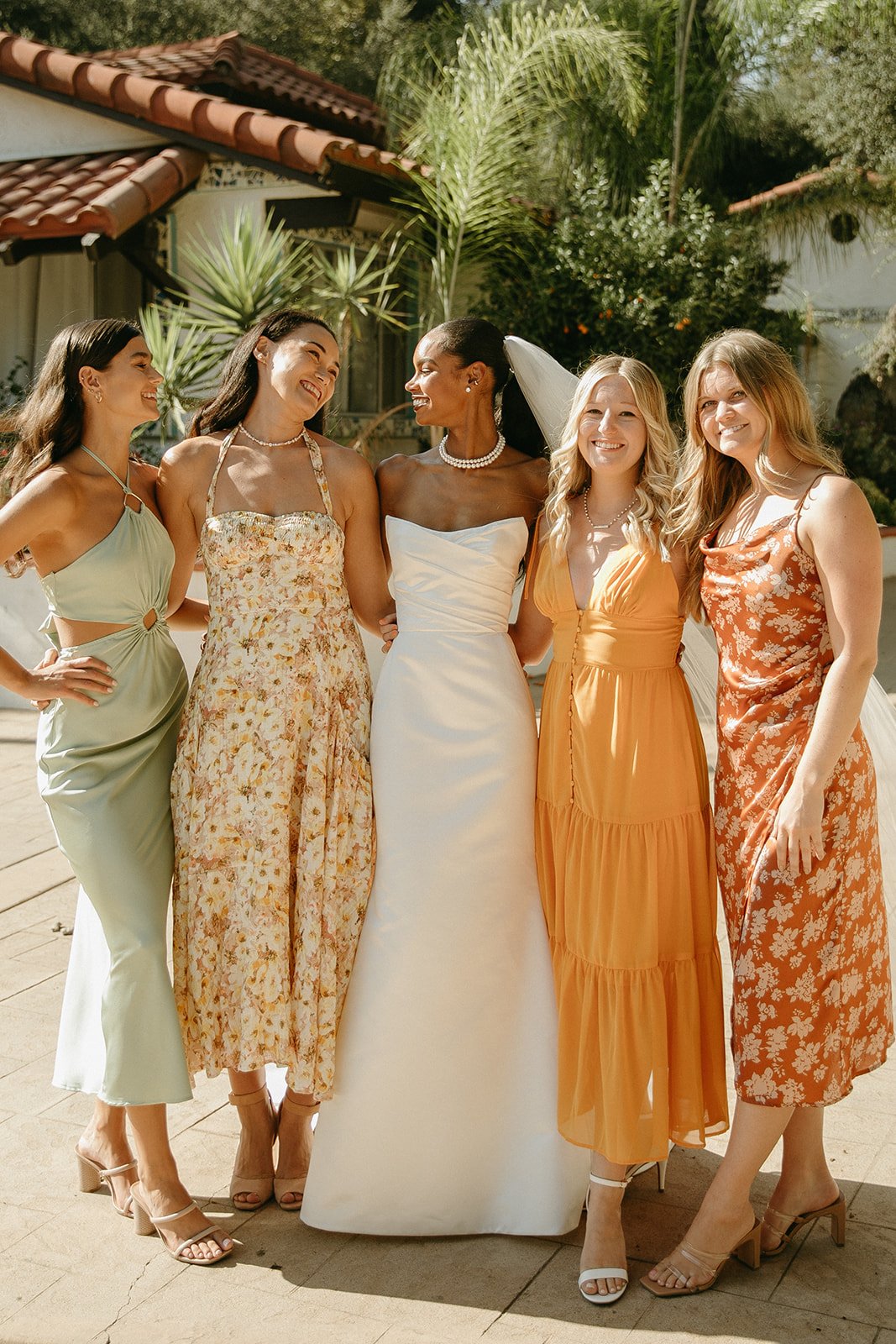 Bride and bridesmaid smiling and posing in colorful dresses