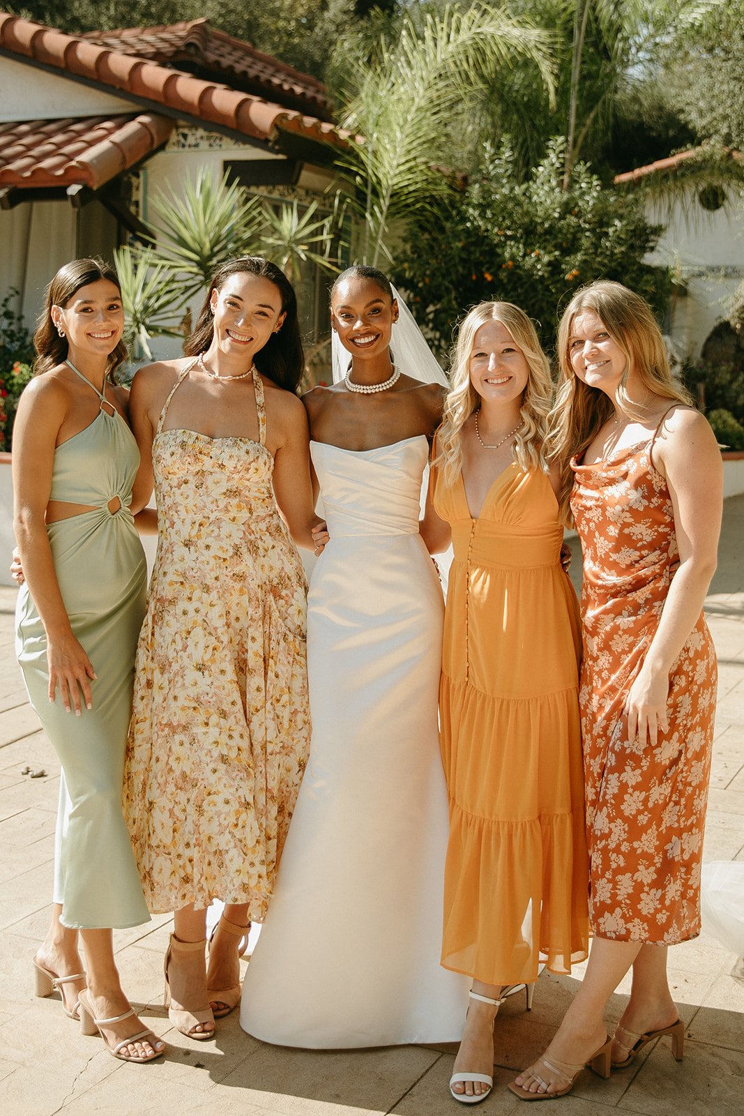 Bride and bridesmaid smiling and posing in colorful dresses