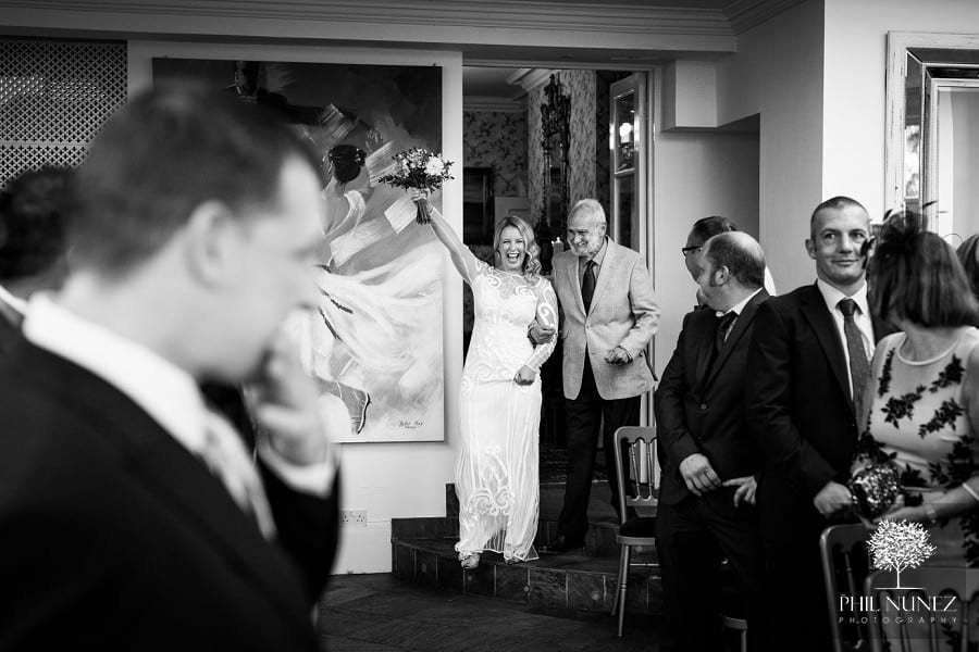A bride raises her bouquet in the air with joy at her Woodhill Hall wedding ceremony. 