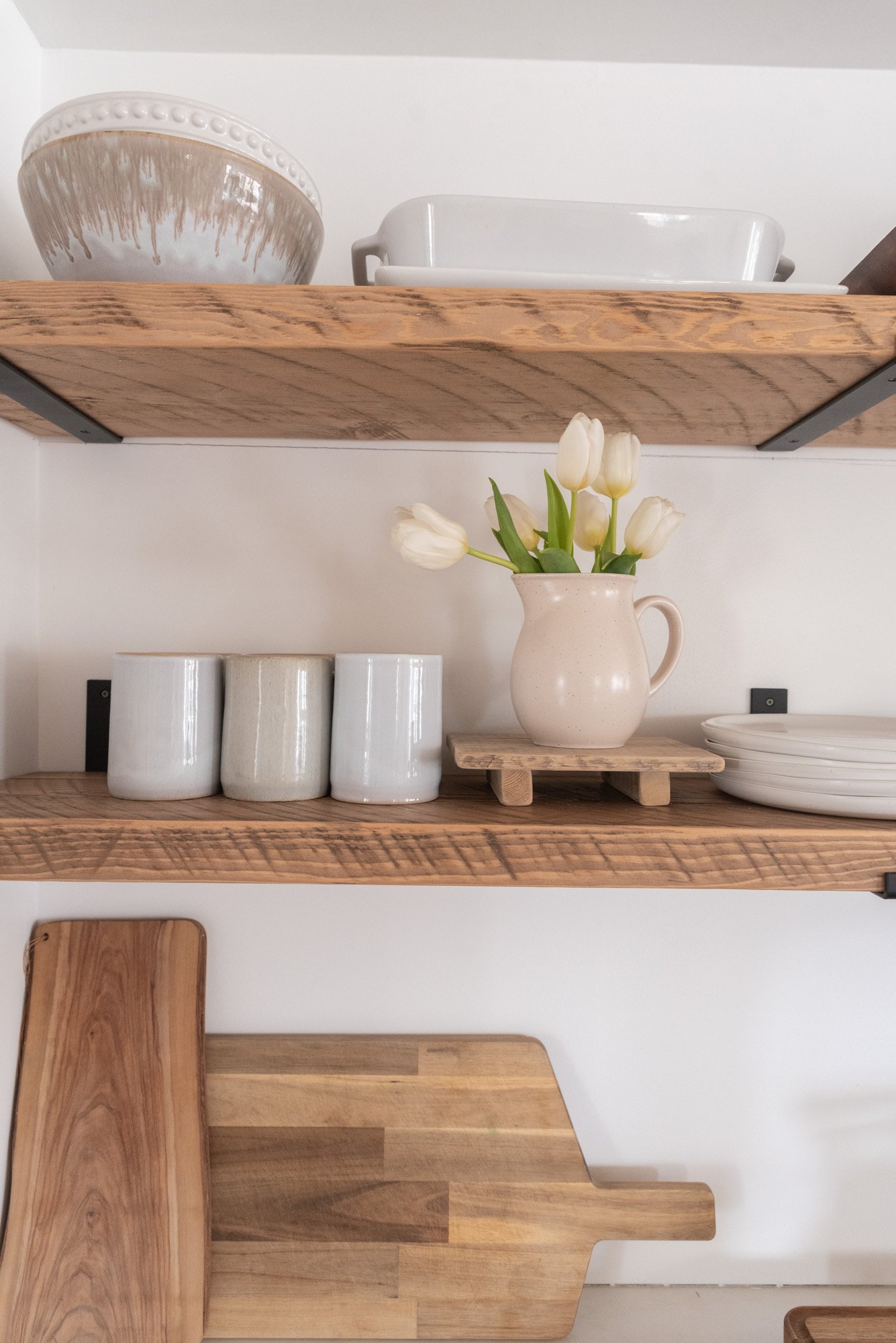 The Wild Decoelis | Kitchen shelves rough sawn with black iron brackets minimal reclaimed wood and white ceramics. tulips on stand