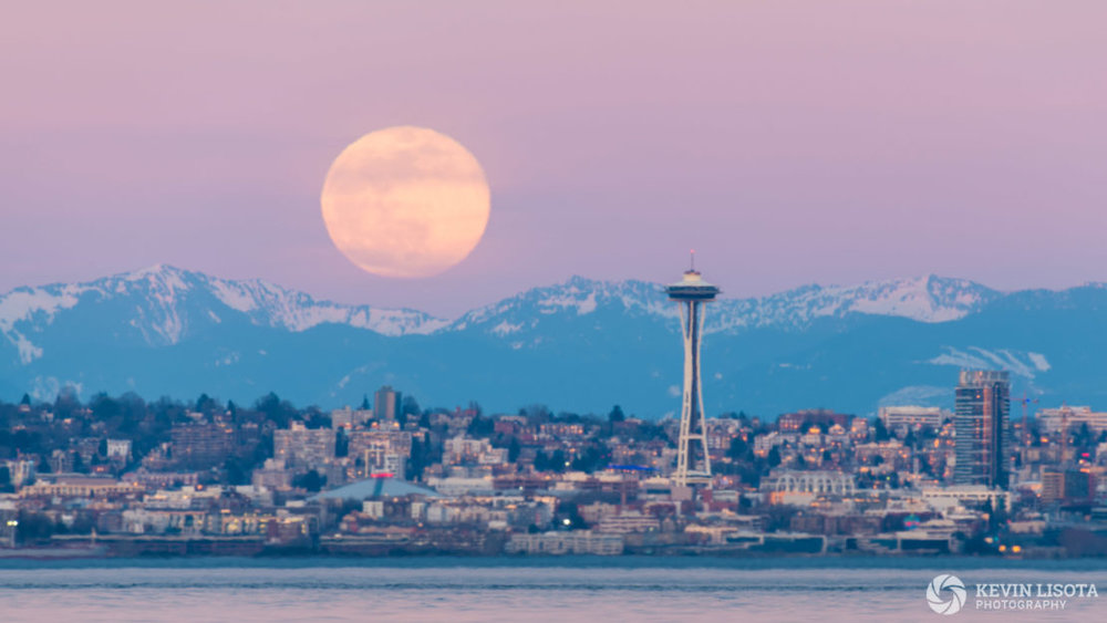 Moonrise over Seattle and the Cascade Mountainss ruined by strong heat distortion when cold air above the waters of Puget Sound mixed with warm air on a summer-like winter afternoon. 500 mm, 1/3 sec, f/10, ISO 80.