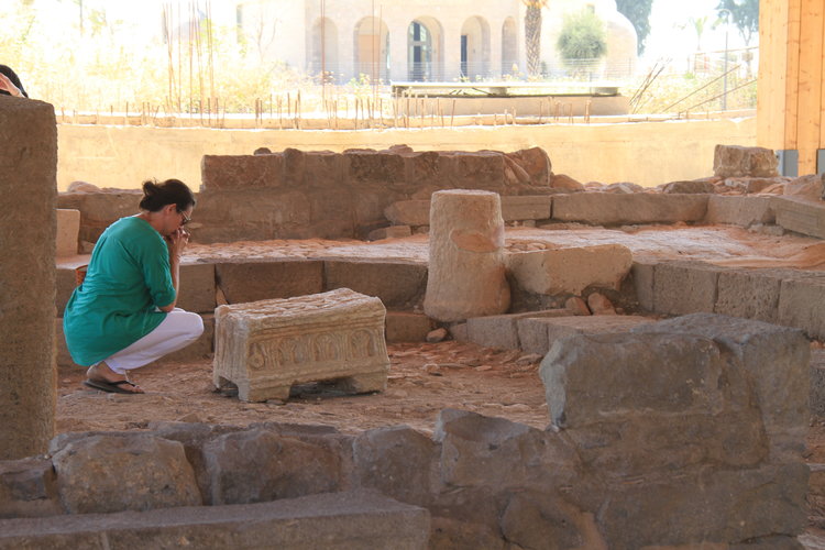 A woman prays next to the Magdala Stone. Credit: Magdala Center and Israel Antiquities Authority.