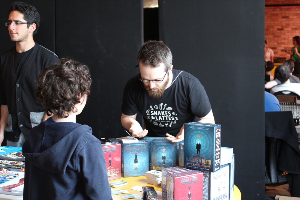 A volunteer from Snakes and Lattes shows off a version of the Machine of Death card game, based on Ryan North's anthology book of the same name. 