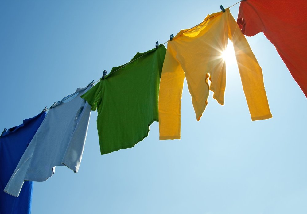  10856478 - colorful clothes hanging to dry on a laundry line and sun shining in the blue sky. 