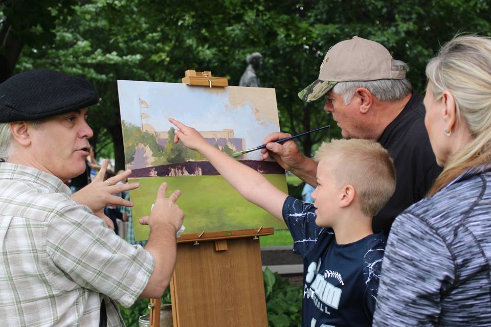 Artist David Geister invites a family to contribute to his painting The Wall That Heals, featuring the traveling replica of the Vietnam Veterans Memorial in Washington, D.C.