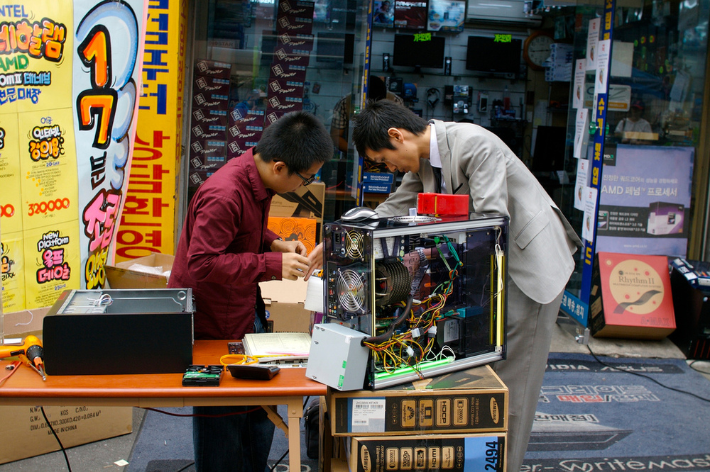 Two guys repairing a computer on an electronic market in Seoul, Korea.