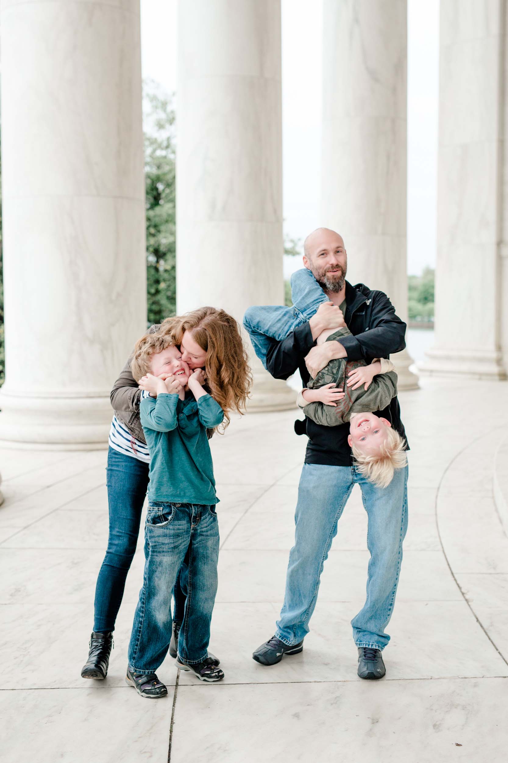 Mom kissing her young son while the father holds their other son on a family trip together in Washington DC, USA