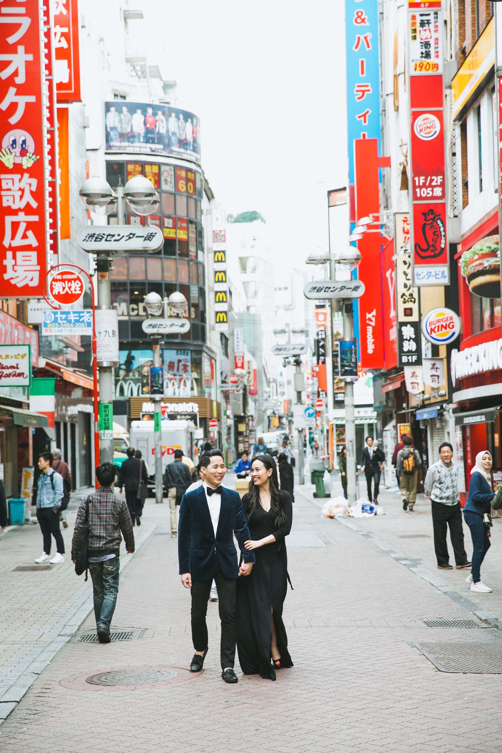 Couple in formal wear standing on busy Tokyo street in Japan on a couples trip