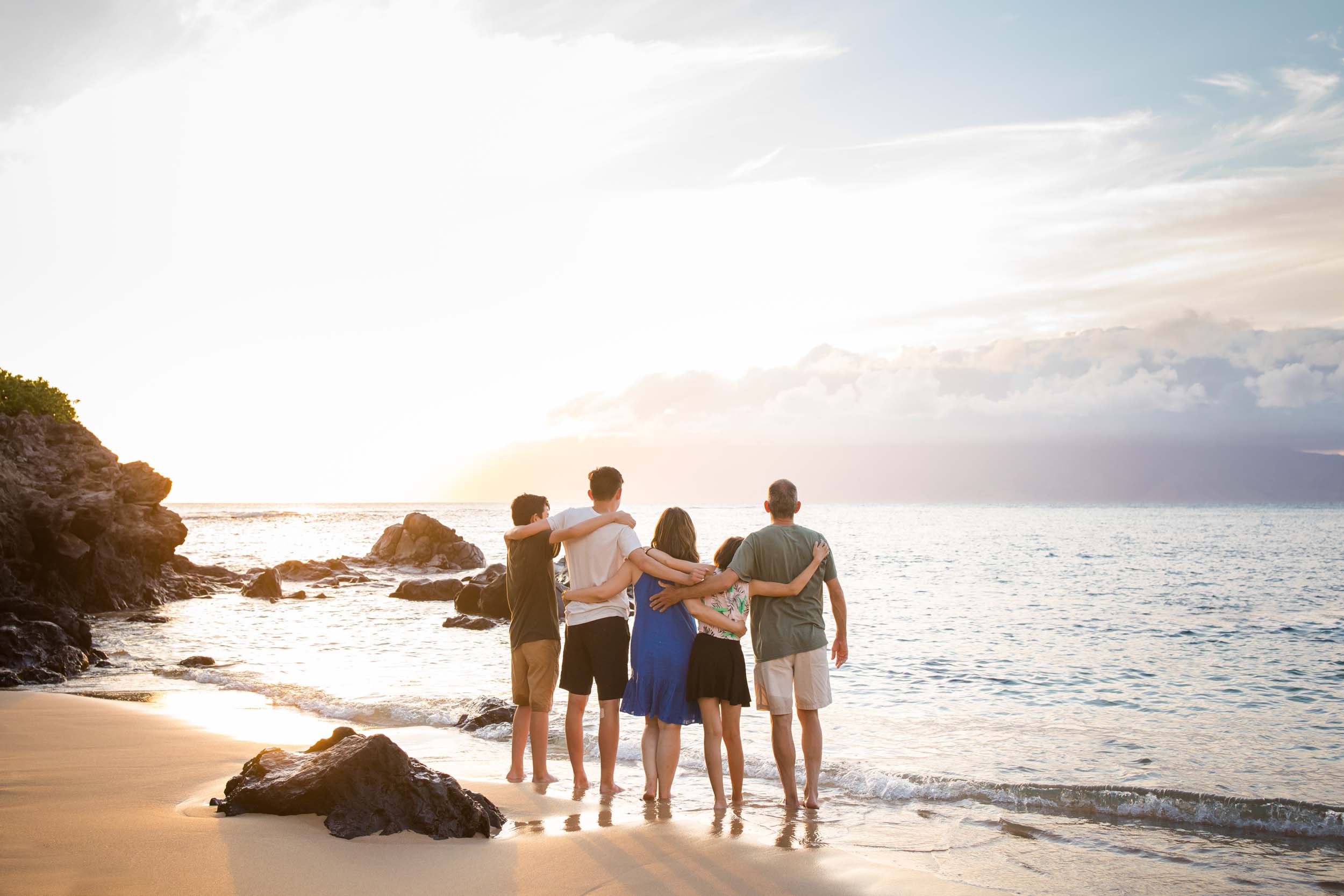 Family staring out at the ocean with their arms around each other in Maui, USA