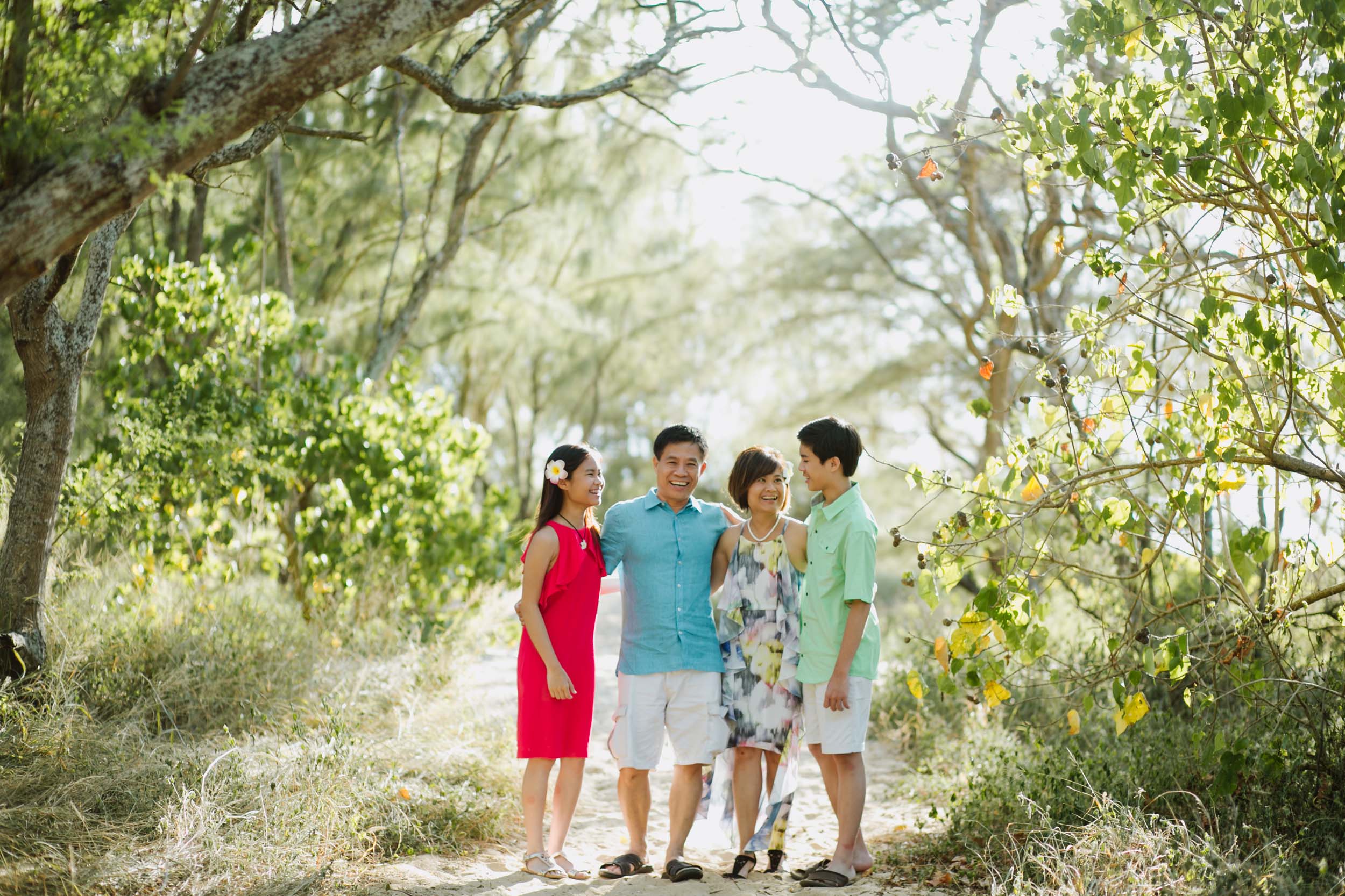 Family standing together along a sandy pathway surrounded by bright green foliage in Maui, USA
