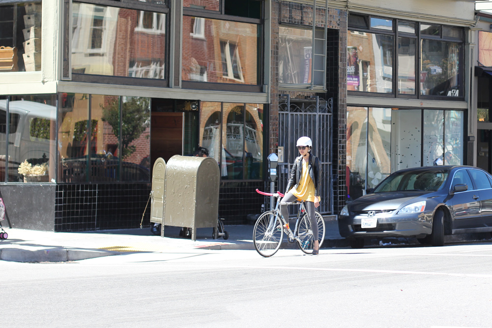 A fashionable woman rides her bike on Valencia Street in San Francisco.