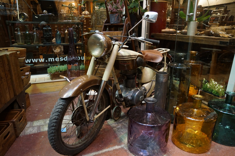 LOVE the juxtaposition of the retro motorbike and amethyst, amber and jade green glass bottles