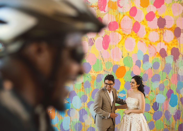 newlywed couple against mural wall as biker rides past altanta georga
