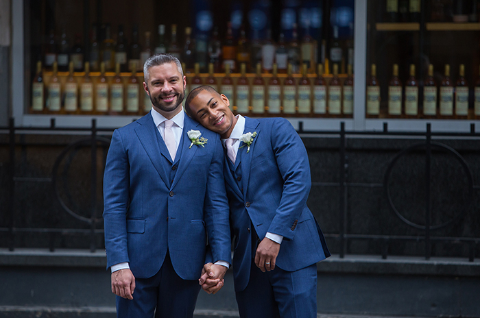 two grooms holding hands in matching suits after their wedding new york city